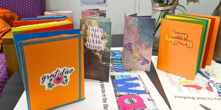 Multiple colourful crafted books stood upright on a table.