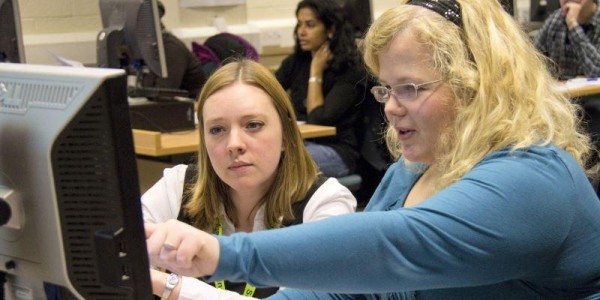 Library staff assisting a student using a computer