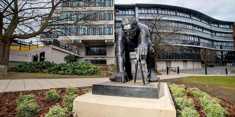 Photograph of Eduardo Paolozzi's sculpture 'Master of the Universe' depicting a figure bent over in thought, outside the Edward Boyle Library on the University of Leeds campus