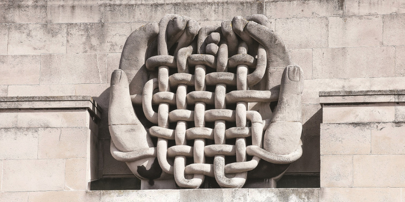 Photograph of Mitzi Cunliffe's sculpture 'Man-made Fibres', two stone hands cradling a woven lattice