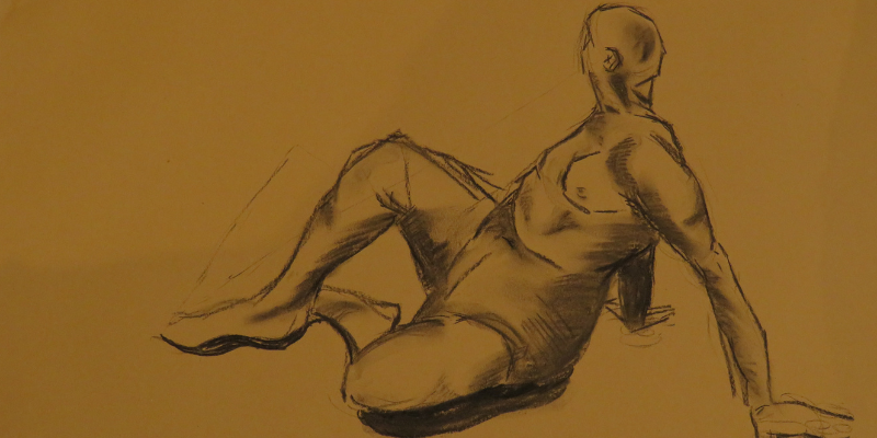 A close crop of a hand holding a pencil and drawing a reclining figure