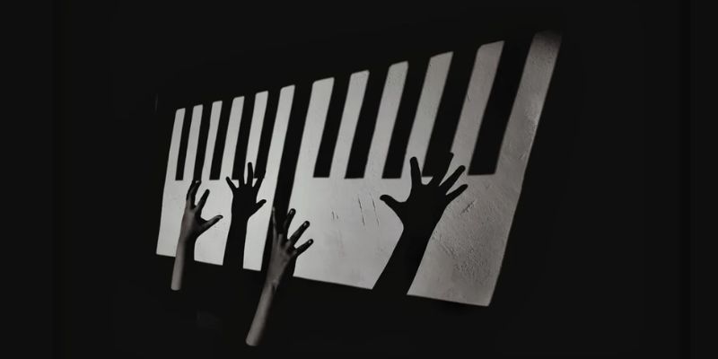 Black and white photograph of disembodied hands playing a piano on a black background.