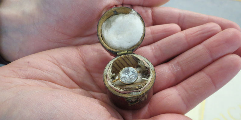 Burns' 'Courting Ring', a twisted gold ring given by Burns to Jean Armour held in staff member's palms.