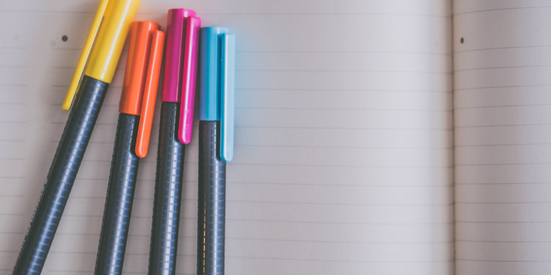 Four different coloured pens on top of a notebook