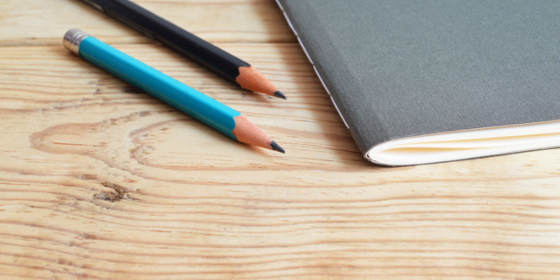 Two pencils next to a notebook