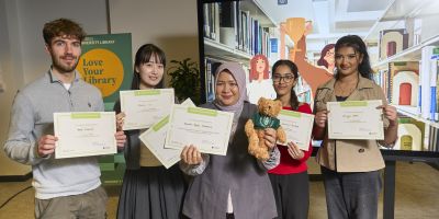 The finalists of the Library Innovation Competition standing in front of competition branded background holding their certificates