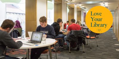 Students study at desks with the Love Your Library logo on the left