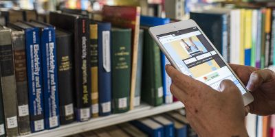 A customer uses Library Search while viewing a shelf in the Laidlaw Library