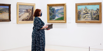 A woman stands in the Stanley and Audrey Burton Gallery looking at the Monet and Seago paintings currently exhibiting on loan from Marks and Spencer.