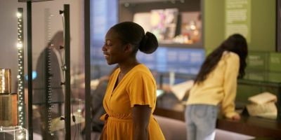 A photograph of people looking at glass museum cases filled with objects.