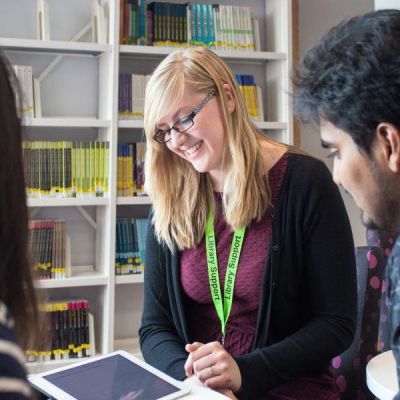 Library staff helping students using an ipad