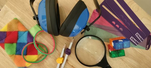 Accessibility tools laid on a table, including magnifying glasses, ear defenders, fidget toys and more.