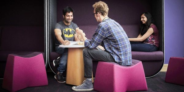 Three students sitting together one of which is using a wooden puzzle