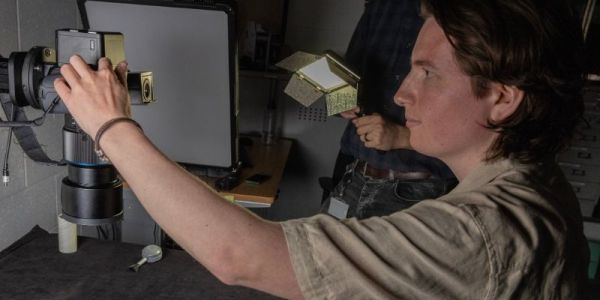 A person, in a dimly lit room, uses a camera.