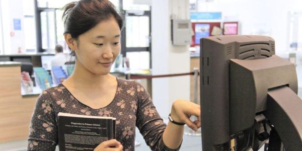 A student borrowing a book using a self service machine
