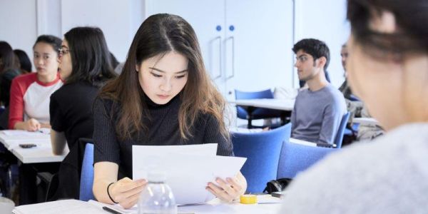 A student attending a Library workshop with others reading a paper document