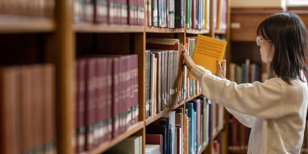 A girl takes a book from a shelf in the Brotherton library