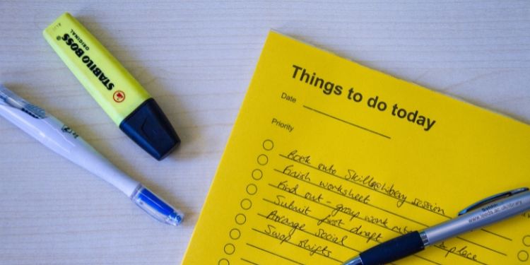 On a table is a to do list with two pens and a yellow highlighter nearby.