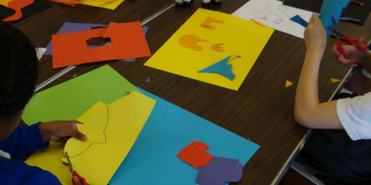 Children cutting up brightly coloured card for an artwork
