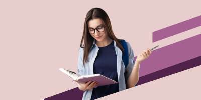 A Masters student reads a book and twirls her pen on a pink background.