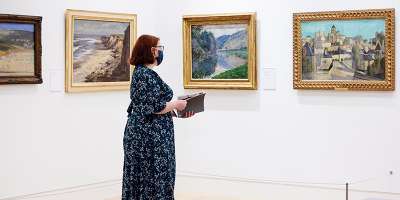 A woman stands in the Stanley and Audrey Burton Gallery looking at the Monet and Seago paintings currently exhibiting on loan from Marks and Spencer.