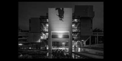 A black and white photograph of the Roger Stevens building, with the Hermes sculpture in the centre of the shot. The photograph is by Simon Phipps