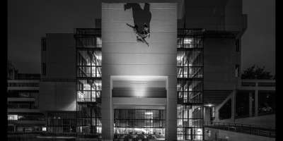 A black and white photograph of the Roger Stevens building, with the 'Hermes' sculpture in the centre of the shot. the photography is by Simon Phipps