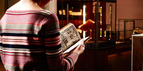 A person look at a book from Special Collections in the Treasures of the Brotherton Gallery