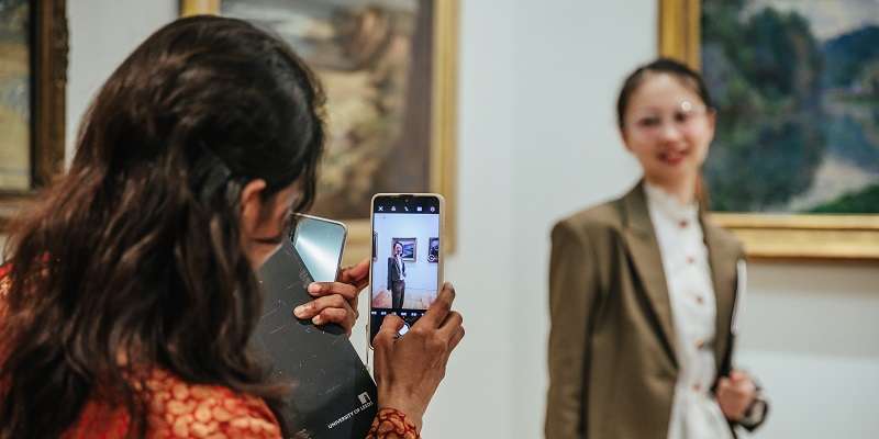 Visitors using a phone to take a photo in the art gallery